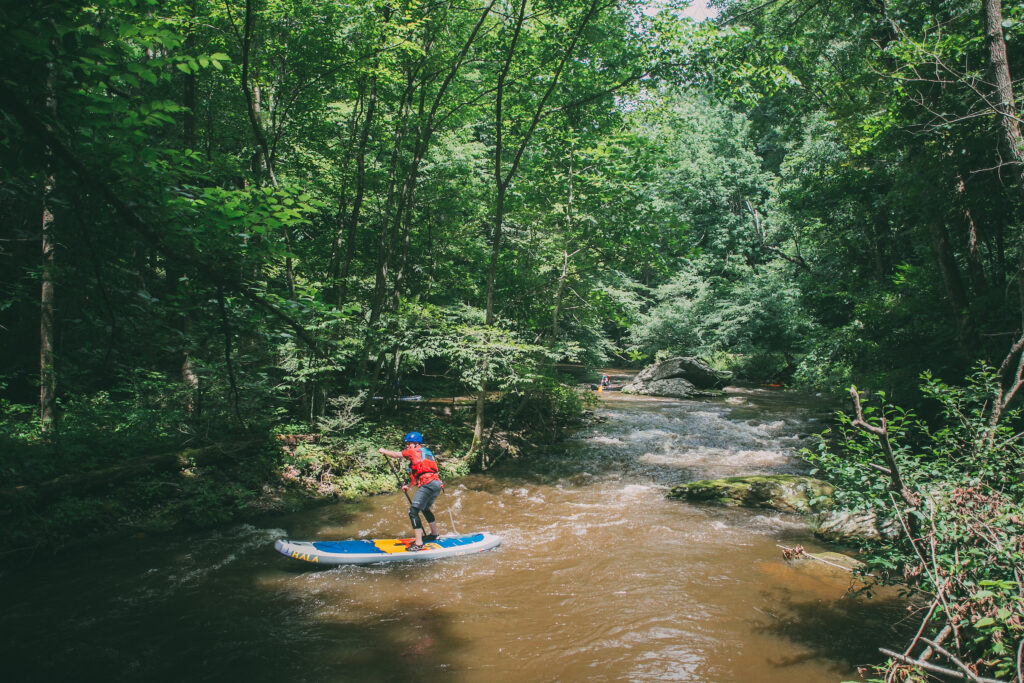 Man on stand-up paddle board navigating a creek