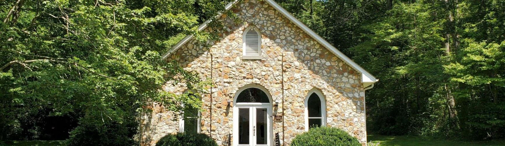 Stone church surrounded by leafy trees