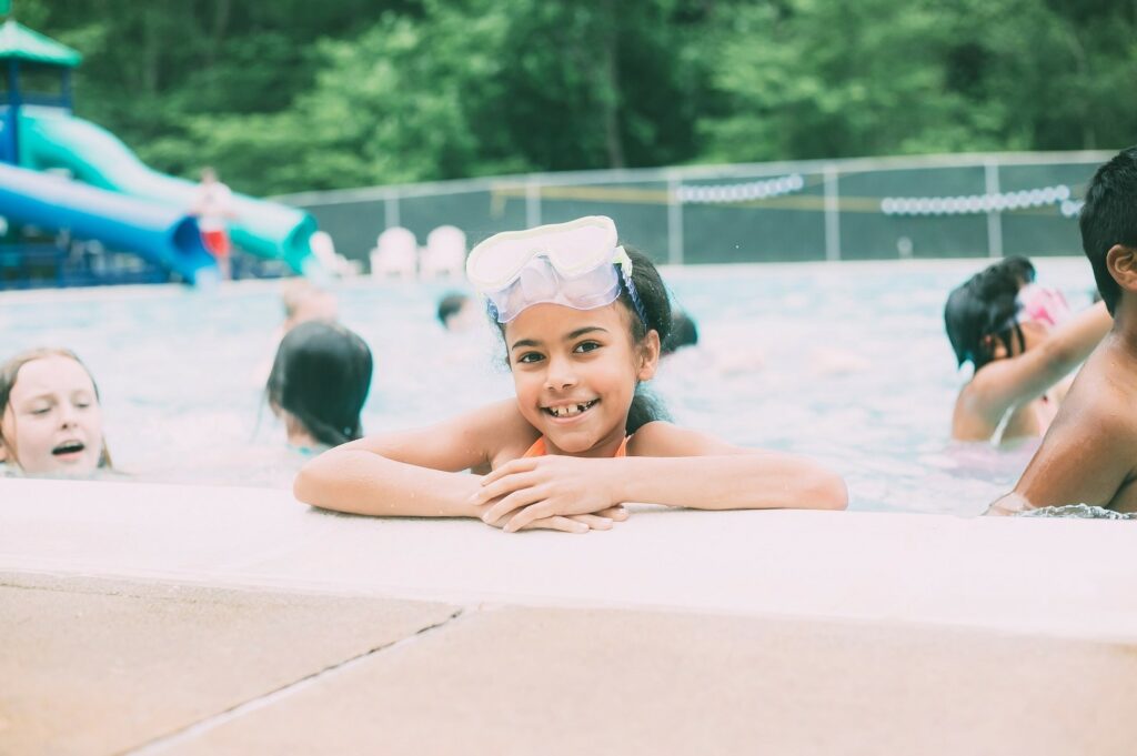 Child in pool with waterslide in background